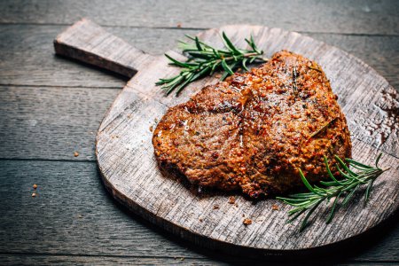 Téléchargez les photos : Grilled beef steak with spices on cutting board on wooden background - en image libre de droit