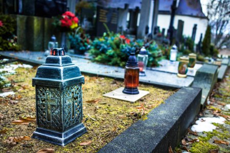 Foto de Candle lantern at grave in cemetery. Grief and paying respect for dead person. Tombstones and a chapel in the public cemetery - Imagen libre de derechos