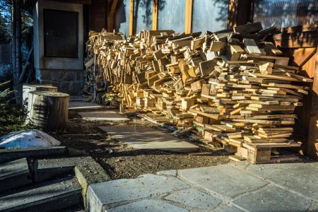 Téléchargez les photos : A pile of stacked firewood, prepared for heating the house, harvested for heating in winter on the house wall - en image libre de droit