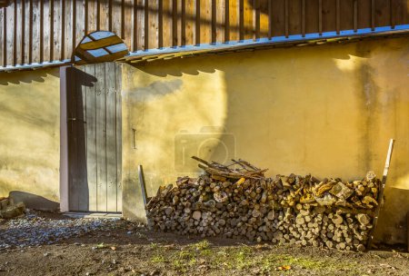 Foto de A pile of stacked firewood, prepared for heating the house, harvested for heating in winter on the house wall - Imagen libre de derechos
