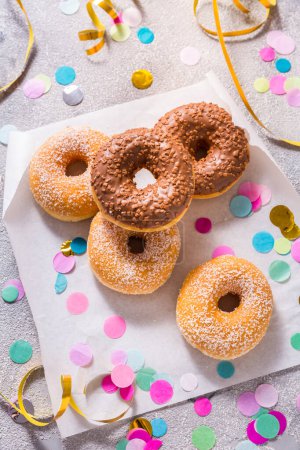 Téléchargez les photos : Krapfen, berliner or donuts with streamers, confetti  for carnival or party on grey background - en image libre de droit