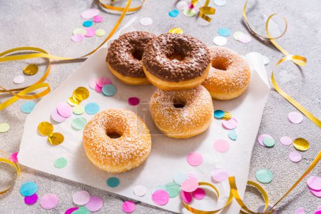 Téléchargez les photos : Krapfen, berliner or donuts with streamers, confetti  for carnival or party on grey background - en image libre de droit