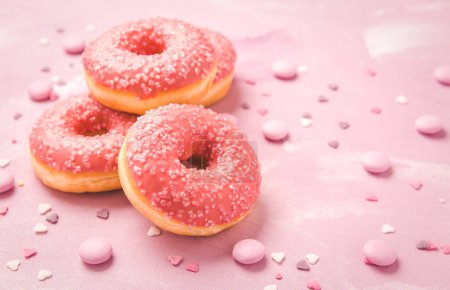 Photo for Pink donuts with sprinkles and pink chocolate beans on pink background - Royalty Free Image