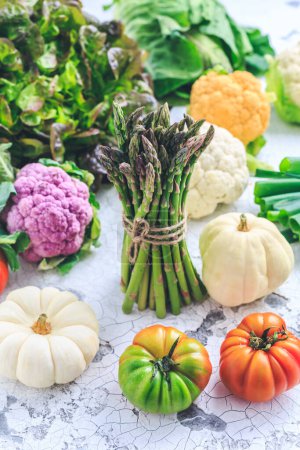 Téléchargez les photos : Assortment of fresh organic vegetables with green asparagus, lettuce,  cauliflower, tomato, pumpkin and green onion - en image libre de droit