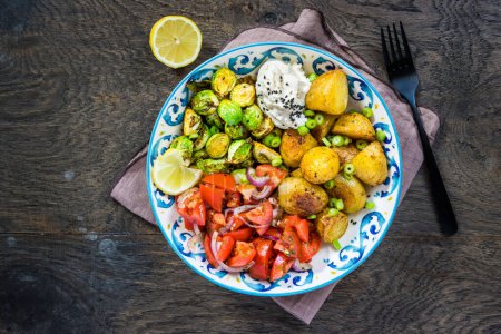 Foto de Brussel sprouts and tomato salad bowl, healthy and balanced food with baked potatoes - Imagen libre de derechos