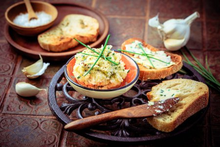 Photo for Homemade garlic bread or baguette slices with garlic butter and herbs on kitchen table - Royalty Free Image