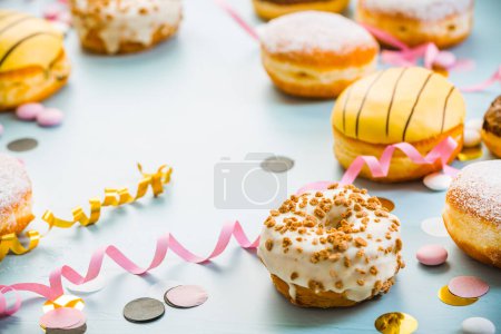 Foto de German Krapfen or donuts with streamers and confetti. Traditional Berliner for carnival and party.. Colorful carnival or birthday image - Imagen libre de derechos