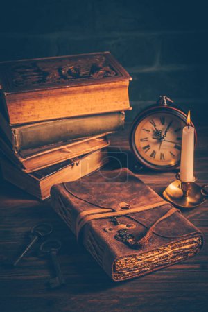 Foto de Old antique books with candle and vintage clock on wooden background - Imagen libre de derechos