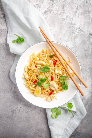 Téléchargez les photos : Mélanger les nouilles frites avec le poulet et les légumes dans un bol blanc. Cuisine de style asiatique. - en image libre de droit
