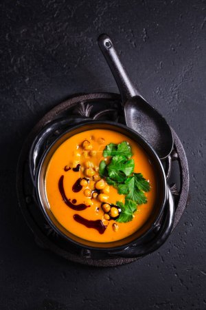 Photo for Creamy Pumpkin cream soup with pumpkin seed oil, baked chickpeas and cilantro - Royalty Free Image