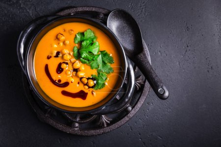 Téléchargez les photos : Creamy Pumpkin cream soup with pumpkin seed oil, baked chickpeas and cilantro - en image libre de droit