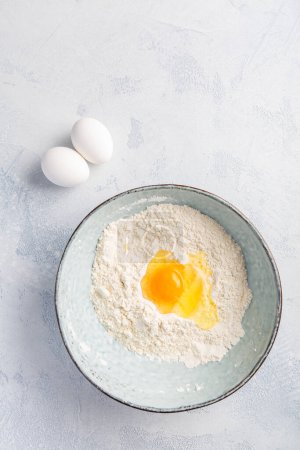 Photo for Flour with egg in bowl - cooking and baking ingredients - Royalty Free Image