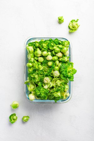 Foto de Fresh  organic green brussels sprouts and small winter cabbage vegetable in glass container, ready to freeze - Imagen libre de derechos