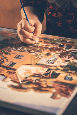 Foto de Una mano con pincel dibujo cuadro de campo con pinturas acrílicas sobre lienzo. Concepto artístico. - Imagen libre de derechos