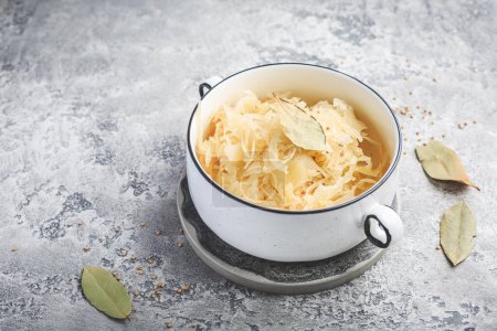 Homemade fermented cabbage or sauerkraut in  a pot on grey background