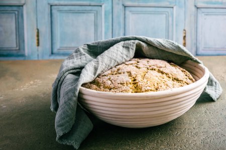 Photo for Homemade spelt bread with herbs and wild garlic, process of raising dough in a special basket. Dough made from natural sourdough, fermentation process - Royalty Free Image