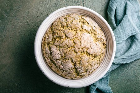 Photo for Homemade spelt bread with herbs and wild garlic, process of raising dough in a special basket. Dough made from natural sourdough, fermentation process - Royalty Free Image