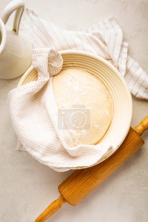 Photo for Raw yeast dough resting and rising in a special basket on kitchen table - Royalty Free Image