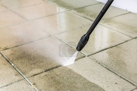 Detail of cleaning terrace with high-pressure water blaster, cleaning dirty paving stones