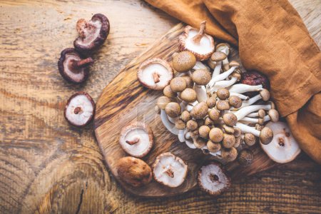 Photo for Raw brown shimeji mushrooms and shiitake on cutting board, edible mushrooms - Royalty Free Image