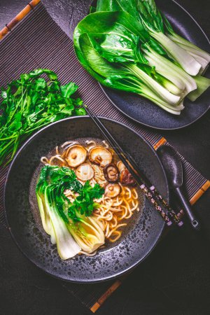 Photo for Freshly prepared vegan ramen soup, full of umami flavours with ramen noodles, shiitake mushrooms and steamed pak choi - Royalty Free Image