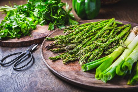 Photo for Fresh green asparagus with green onion and herbs on wooden table - Royalty Free Image