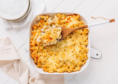 Photo for Mac and cheese in casserole on white kitchen table - Royalty Free Image
