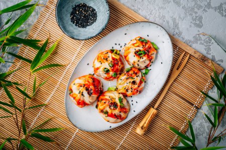 Photo for Steamed dumplings Dim Sum with  hot Sriracha sauce and green onions and sesame seeds. - Royalty Free Image