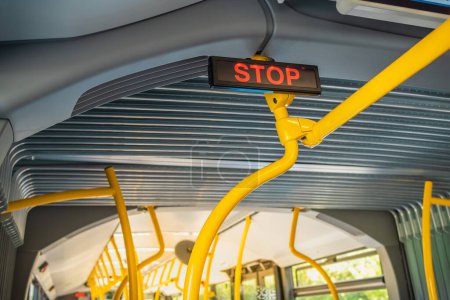 Photo for Stop sign in city bus. Empty bus interior. Bus with blue seats and yellow handrails - Royalty Free Image