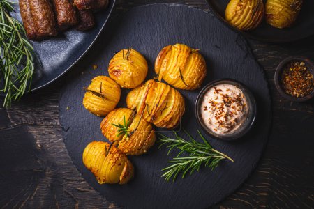 Photo for Hasselback potatoes (potato fans) with additional herbs, spices and whipped feta dip - Royalty Free Image