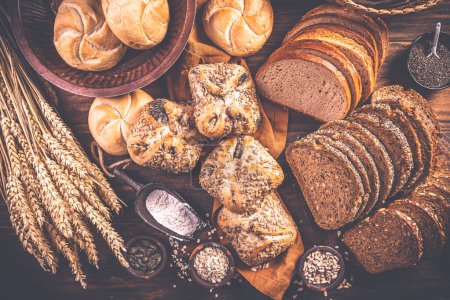 Photo for Assortment of different kind of cereal bakery - bread, pasties, buns, with healthy seeds on wooden background - Royalty Free Image