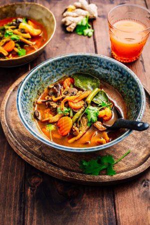 Téléchargez les photos : Curry végétarien rouge thaïlandais aux champignons et légumes sur table en bois - en image libre de droit