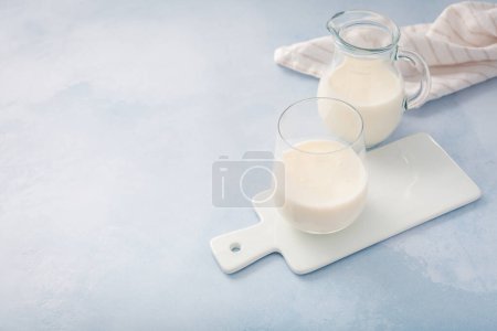 Téléchargez les photos : Babeurre, kéfir, yaourt aux probiotiques, ayran en verre et pot. Boisson laitière fermentée froide probiotique. Aliments et boissons à la mode. - en image libre de droit