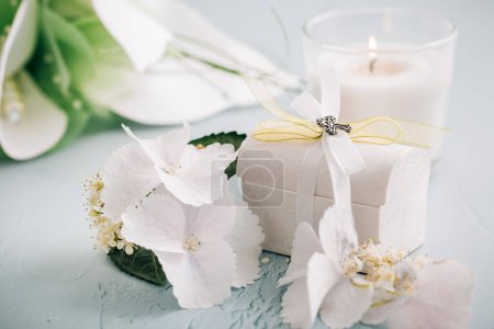 Téléchargez les photos : Confirmation ou premier concept de communion sacrée - petit cadeau avec bougie et fleurs - en image libre de droit