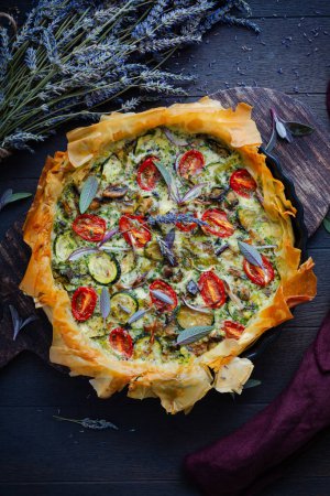 Photo for Delicious vegetarian summer quiche with zucchini, tomato, mushrooms, sage and lavender with phyllo pastry - Royalty Free Image