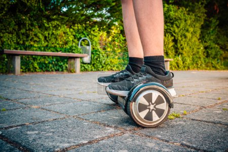 Téléchargez les photos : Adolescent chevauchant un hoverboard à la cour d'école scooter auto-équilibrage, planche lévitante utilisée pour le transport personnel - en image libre de droit