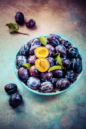 Photo for Fresh plums on plate over dark stone background - Royalty Free Image