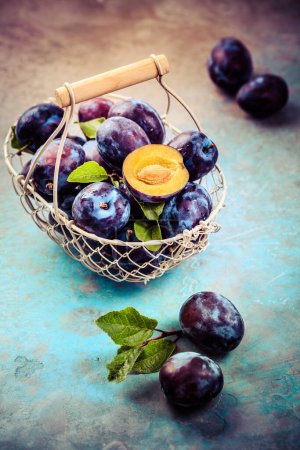 Photo for Fresh plums in basket on dark stone background - Royalty Free Image