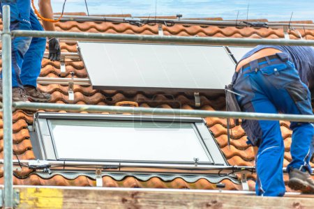 Téléchargez les photos : Installation de panneaux solaires sur un toit. Panneaux solaires sur le toit. Travailleurs installant des cellules solaires. - en image libre de droit