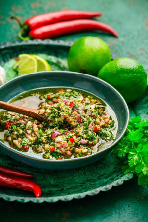 Photo for Raw homemade Argentinian green Chimichurri or Chimmichurri salsa or sauce made of parsley,  cilantro, chili, garlic, oregano, olive oil and red wine vinegar - Royalty Free Image