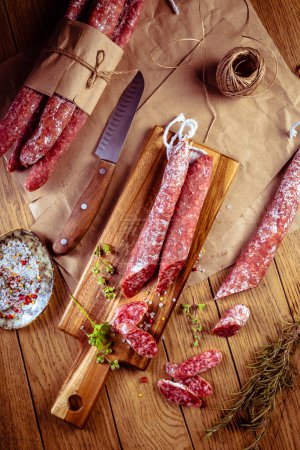 Photo for Traditional Spanish fuet on wooden background. Dry cured pork sausages with delicate taste. - Royalty Free Image