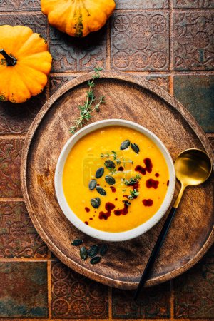 Photo for Pumpkin soup with pumpkin seeds  and pumpkin seed oil served in bowl on rustic kitchen table - Royalty Free Image