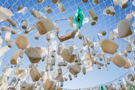 Foto de Contenedores de plástico en la red de pesca contra el cielo azul - concepto de basura, contaminación del agua, cuestión ambiental - Imagen libre de derechos