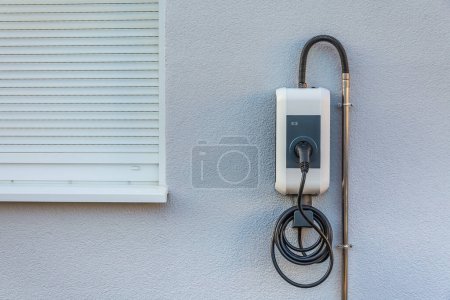 Téléchargez les photos : Wallbox sur un mur de la maison familiale pour une charge confortable de la voiture électrique - en image libre de droit