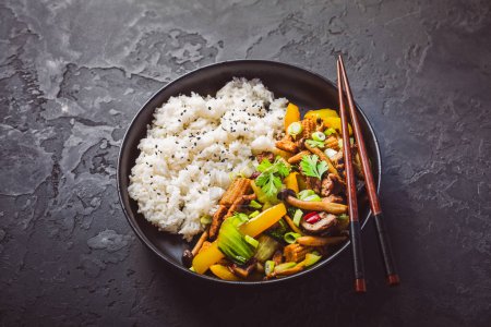 Photo for Stir-fry with mushrooms, vegetables and rice on dark background. Asian style food - Royalty Free Image