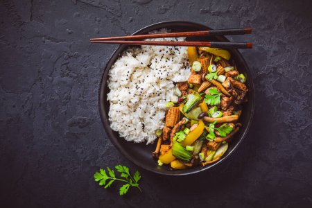 Foto de Remover-freír con champiñones, verduras y arroz sobre fondo oscuro. Comida de estilo asiático - Imagen libre de derechos