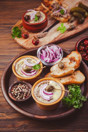 Photo for Fresh homemade chicken liver pate in ceramic bowls and appetizers on rustic background - Royalty Free Image