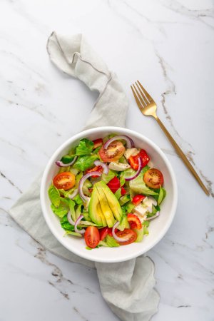 Photo for Healthy green salad with avocado, tomatoes, mozzarella and red onions - Royalty Free Image