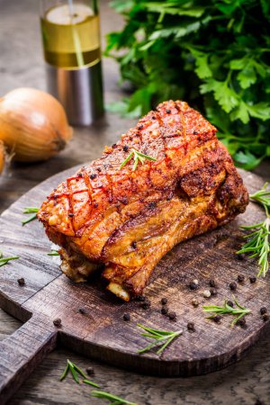 Téléchargez les photos : Ventre de porc grillé à la peau croustillante, avec oignon et herbes sur fond de bois - en image libre de droit