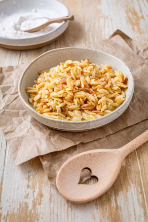 Cooked italian pasta, risoni, orzo in a bowl on wooden table